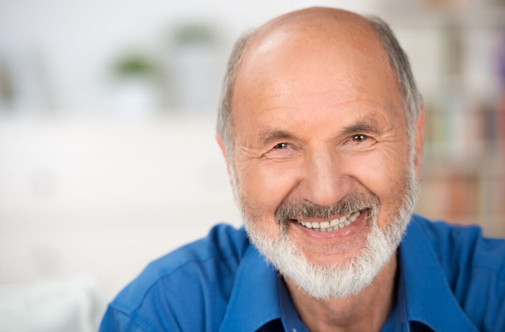 An older adult man with blue polo shirt, smiling and looking directly at the camera