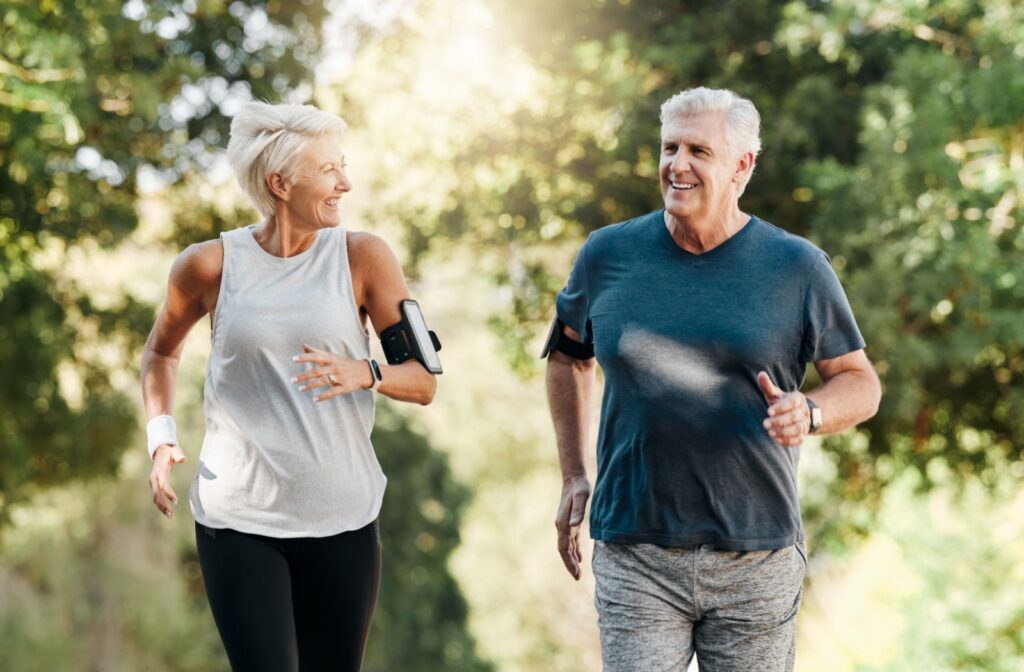 An older couple are jogging together outdoors.